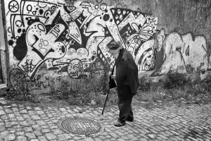Old man walking and graffiti covered wall. Porto, Portugal.
