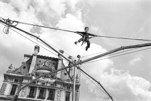 Boy suspended on carnival ride. Tuileries Garden, Paris, France. Louvre in the background.