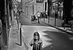 Paris, France. Organ Grinder and girl on scooter.