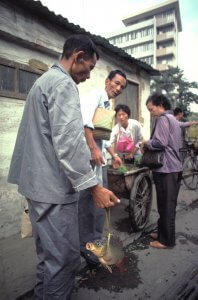 Man carrying live fish from market. China 1984