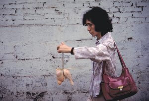 Woman carries chicken home from market. China 1984.