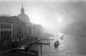 Black and white photo of Fog on canal with boats. Venice Italy.